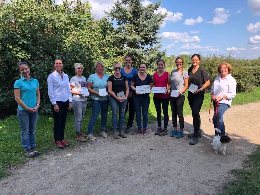 Gruppenfoto im Freien: mehrere Frauen mit Urkunden, daneben ein kleiner Hund